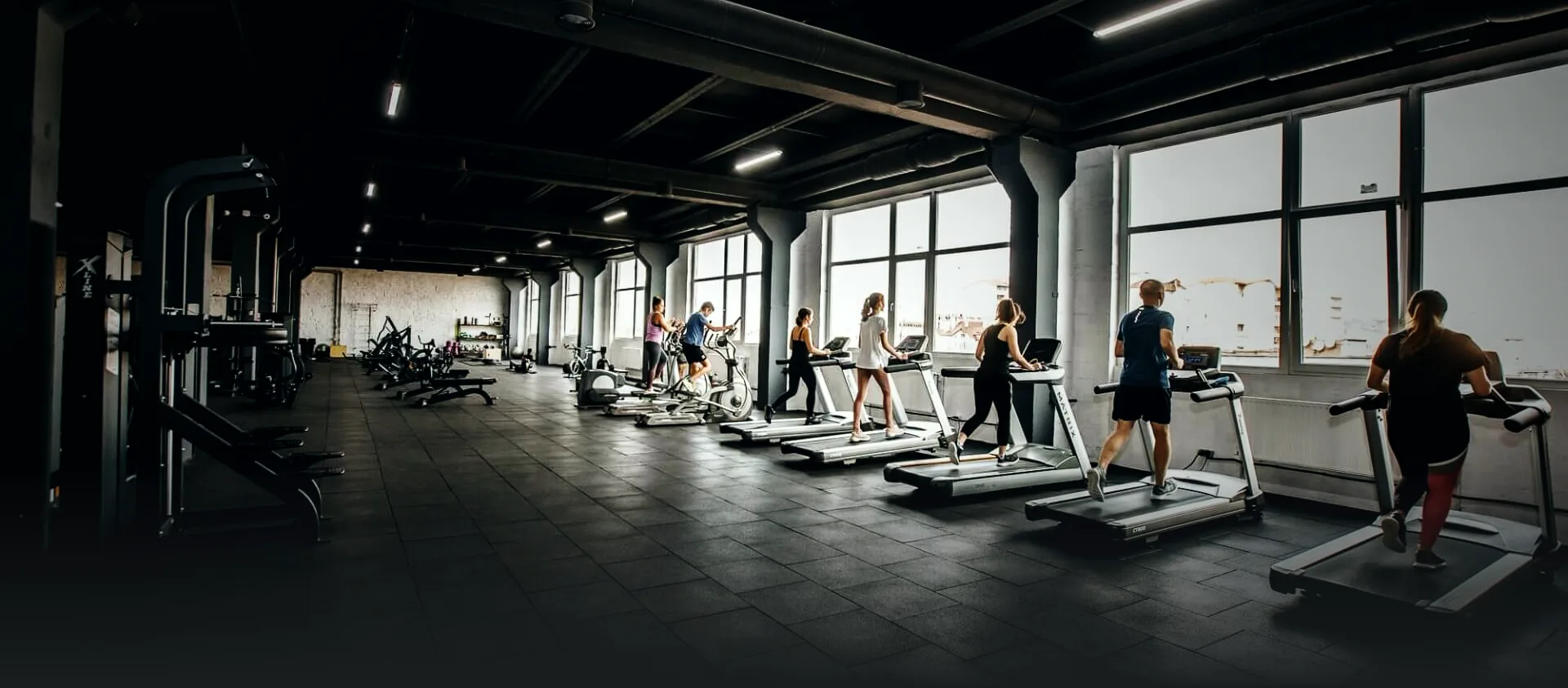 Простір FitMe: ряди бігових доріжок під панорамними вікнами, члени клубу на тренуванні